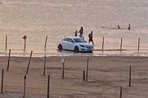 Watch as frantic beachgoers try to rescue stranded cars from rising tide on beach at..