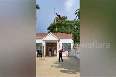 Acrobat climbs up 6-metre-long bamboo stick being held aloft by friend