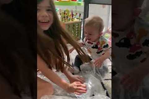 Toddler giggles uncontrollably as mom pops the packing bubbles