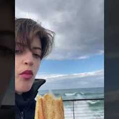 Rogue wave splashes over railing and drenches woman snacking on baguette