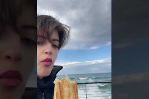 Rogue wave splashes over railing and drenches woman snacking on baguette